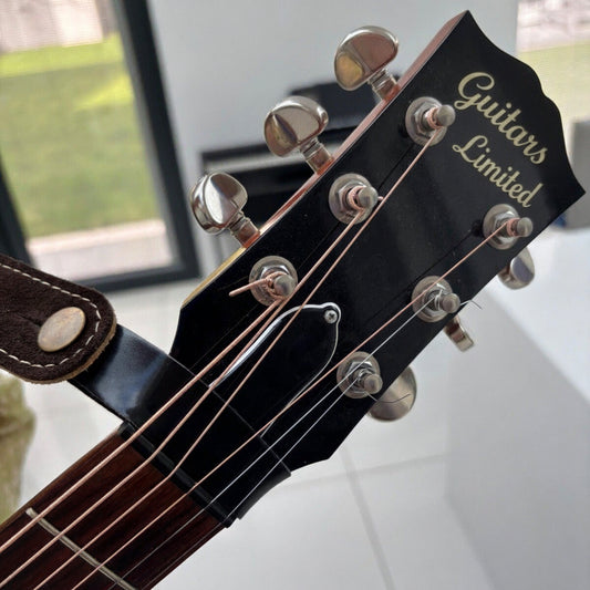 Black Guitar Headstock Tie / Strap photographed on an acoustic guitar in a lounge.