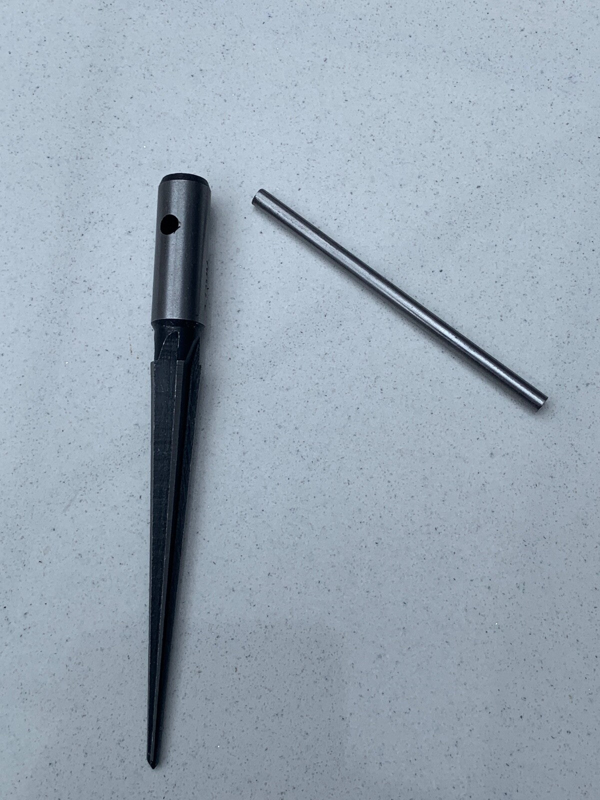 Guitar Hole Reamer showing its handle separated from its body against a grey background.