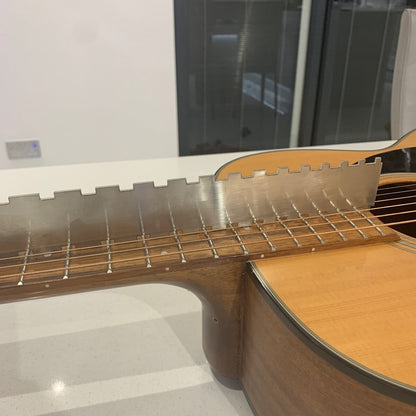 Close-up of a Guitar Notched Straight Edge being used high on a guitar neck in a white room.