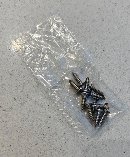 A packet of electric guitar control cover screws on a grey background.