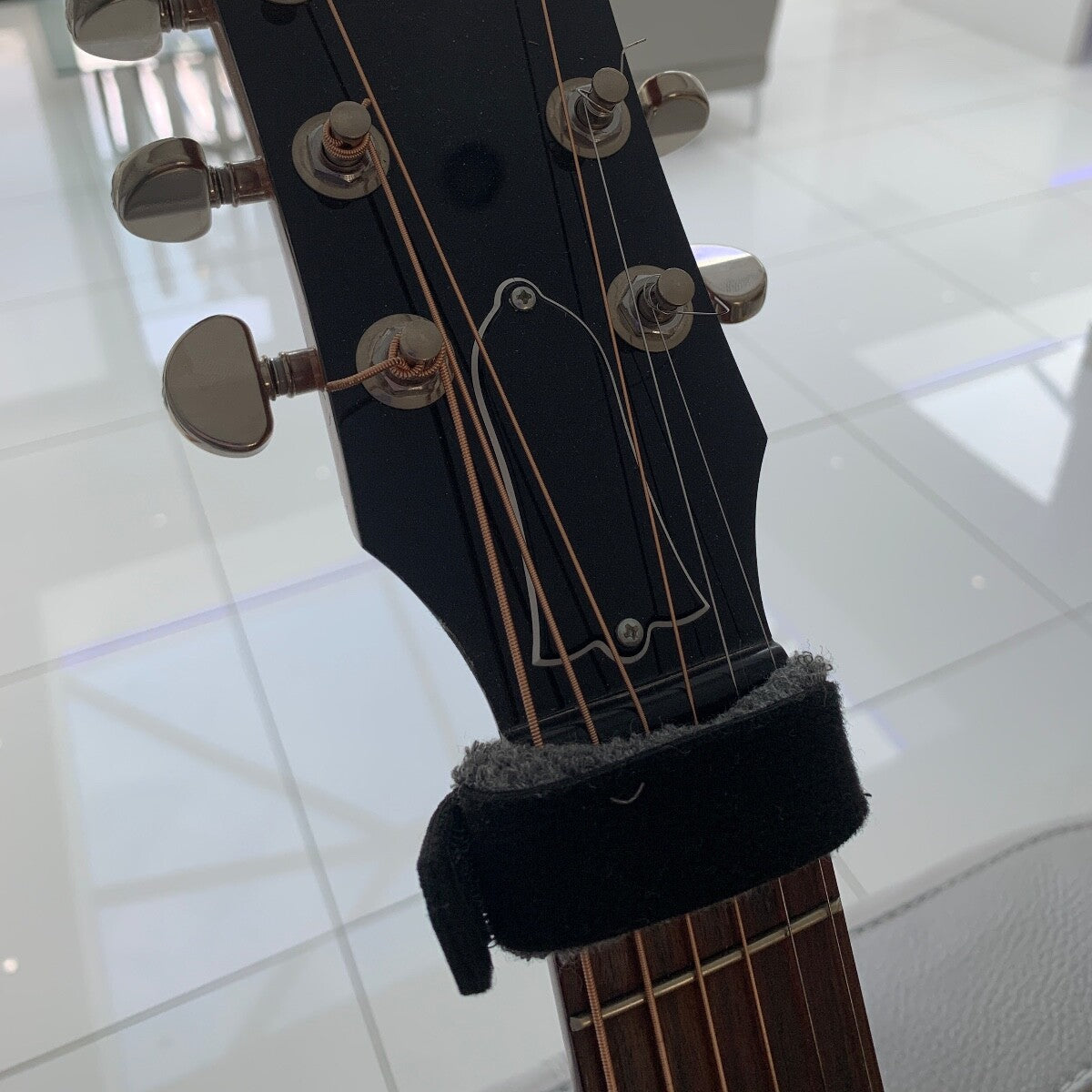 Close-up of a Guitar Muter/Damper photographed on guitar's headstock from the front.