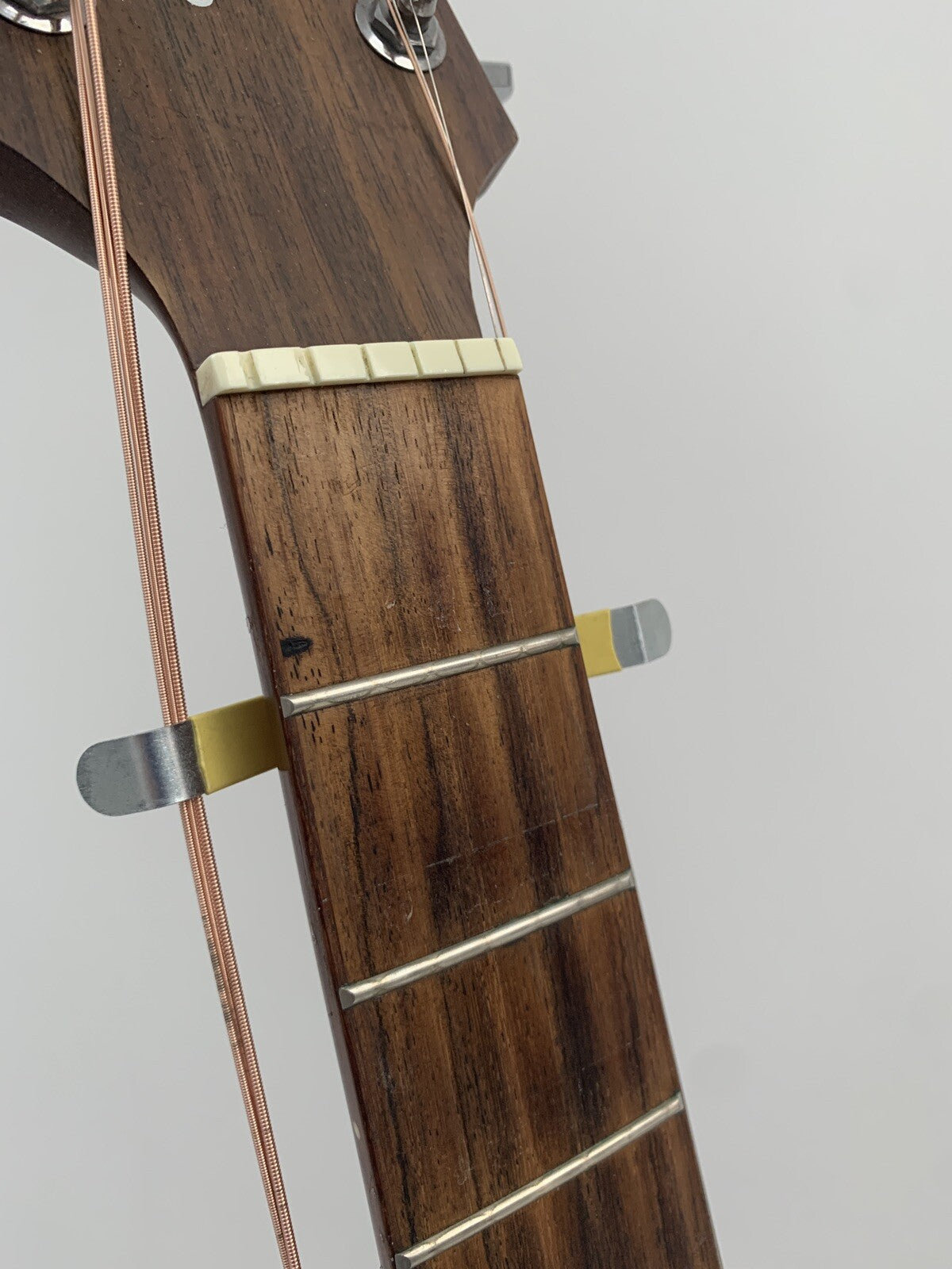A Guitar String Spreader on  the top of a acoustic guitar's neck.
