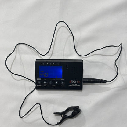 Black guitar tuner / metronome with clip on sensor on a white fabric background
