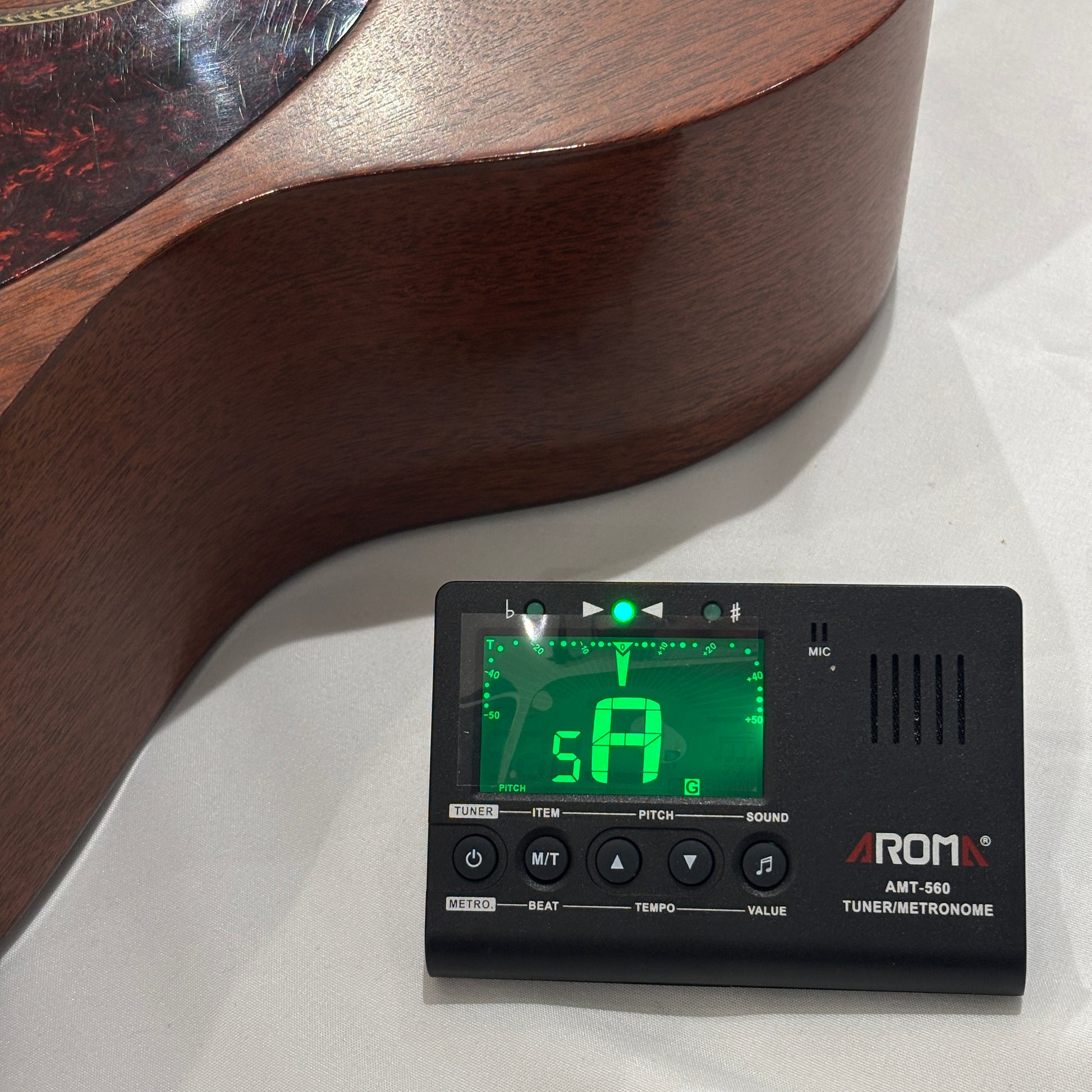 Guitar tuner / metronome on a white surface with a guitar