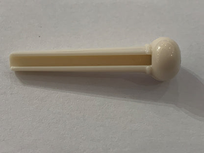 White plastic Acoustic Guitar Bridge Pin with a black dot a white surface.