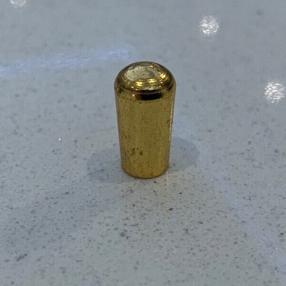 Gold metal electric guitar Toggle Switch Tip on a grey background.