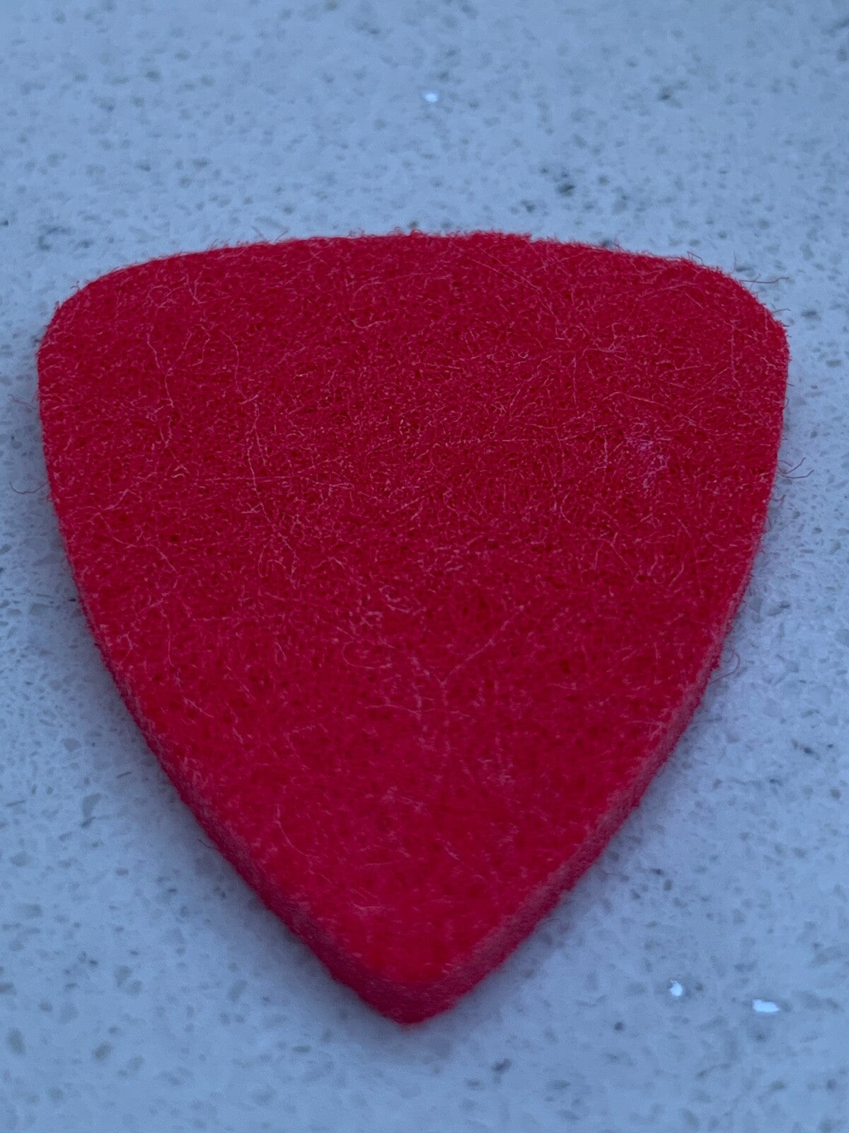 Red Felt Ukulele Pick / Plectrum on a light grey surface