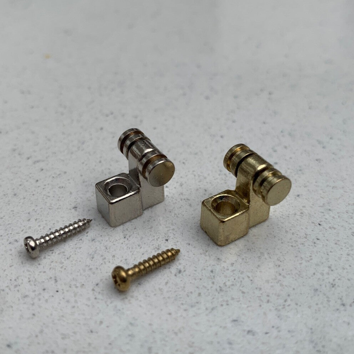 Two Roller Guitar String Tree / Retainers on a grey background.