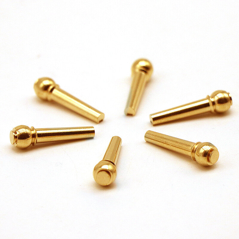 Six Acoustic Guitar Brass Bridge Pins arranged in a circle against on a white background.