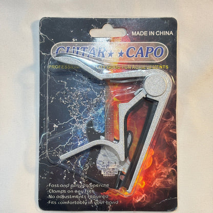 Guitar capo on a black card with colorful design on a white background.